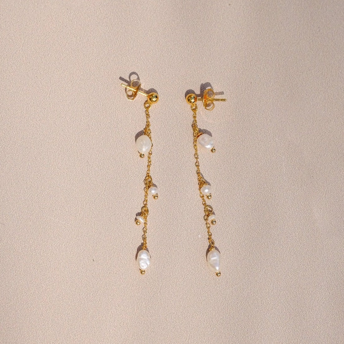 Boucles d'oreilles "Encourage" composé de deux puces d'oreilles agrémentés de perles d'eau sur une chaine forçat, le tout doré à l'or fin.